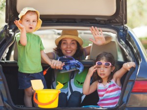 Family sitting in the back of a car smiling to camera and waving.