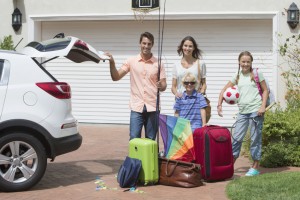 Portrait of smiling family packing car in sunny driveway